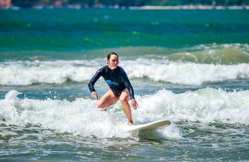 Eine Surferin im blauen Lycra fährt Weißwasser in der Weligama Bay