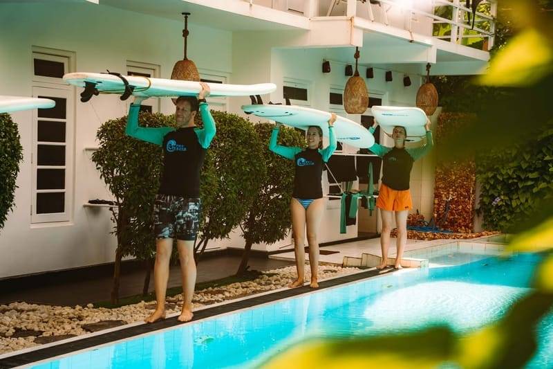 Gäste tragen ihre Surfboards am Pool des The Surfer Beach Camp vorbei, Weligama, Sri Lanka