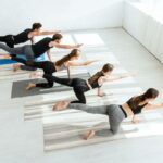 high angle view of five young people practicing yoga in balancing table pose