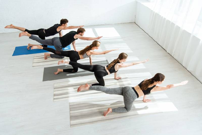 high angle view of five young people practicing yoga in balancing table pose